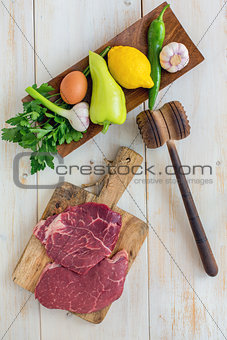 Raw beef for schnitzel and vegetables on wooden plate. View from