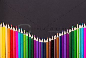 Color pencils arrangement on black