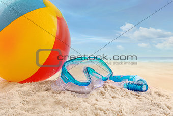 Beach ball and goggles in the sand