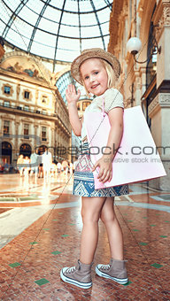 Happy little fashion monger with pink shopping bag hand waving