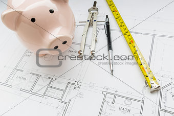 Bank, Compass, Pencil and Measuring Tape Resting on House Plans