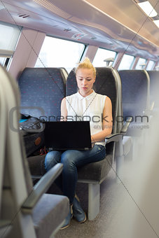 Woman travelling by train working on laptop.