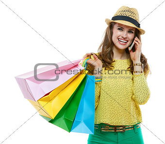Smiling woman in hat with shopping bags talking cellphone