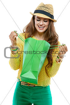 Smiling woman in hat looking inside of the green shopping bags