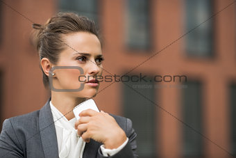 Pensive business woman near office building talking smartphone