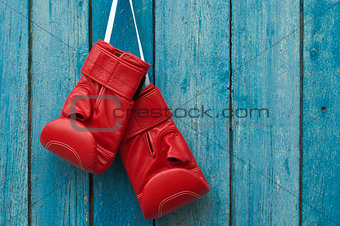 Pair of boxing gloves hanging in a rustic wooden wall