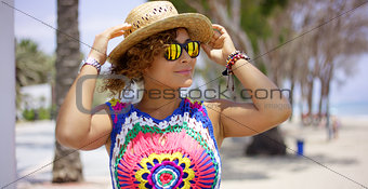 Pretty woman in sunglasses adjusting hat