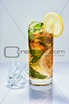 Lemon drink with ice in a glass on white surface