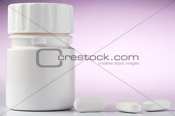 Bottle of aspirin drugs and three pills in the foreground