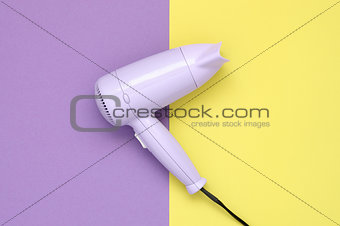 Purple hair dryer on purple and yellow background