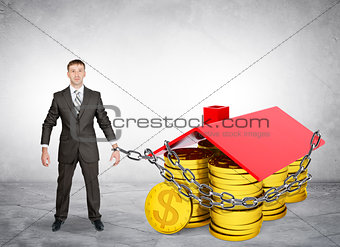 Businessman chained to house with coins