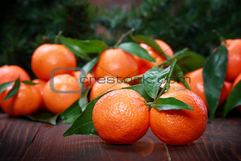Tangerines with leaves on wooden surface