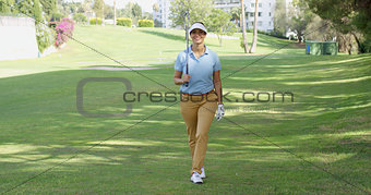 Smiling friendly woman golfer walking on a course