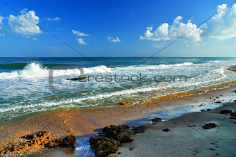 Seascape, cloudy sky, big waves and stones