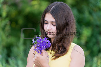 Girl 14 years old looking at bouquet of wildflowers