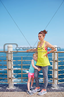 Portrait of mother and child in fitness outfit on embankment