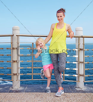 Fitness mother and child standing on embankment and handwaving