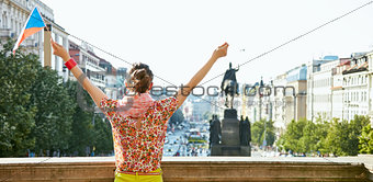 Seen from behind young woman with Czech flag rejoicing in Prague