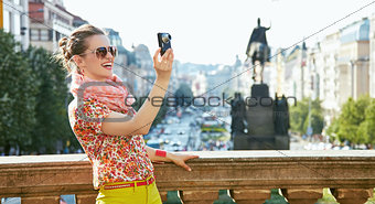 Smiling woman taking photos with digital camera in Prague