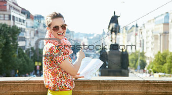 Woman with map pointing on statue at Wenceslas Square in Prague