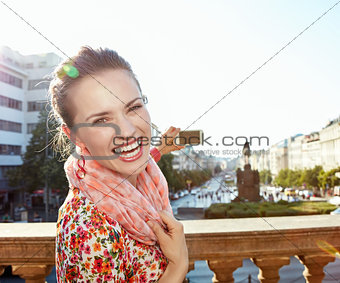 Portrait of happy woman taking photos with cellphone in Prague