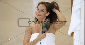 Young woman drying her long dark brown hair