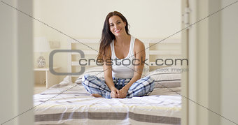 Woman in plaid pajamas sitting on bed