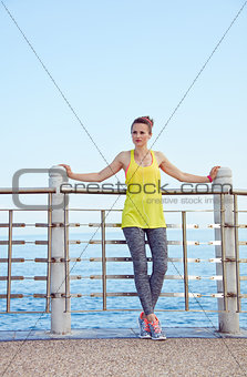 young woman in fitness outfit looking aside at embankment