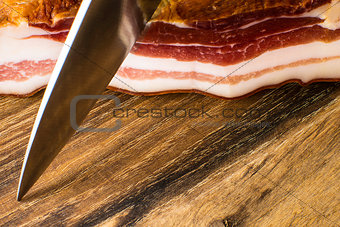 Smoked Bacon on Vintage Wooden Board With a Knife Ready to Cut