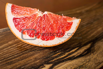 Slice of Red Juicy Grapefruit on Vintage Wooden Board