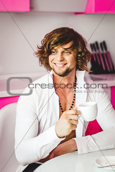 Man with white cup in the pink kitchen