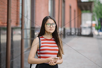 Young Asian woman with glasses hold smartphone in hands.