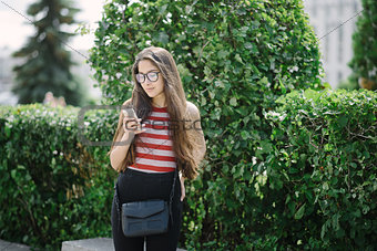 Young Asian woman with glasses using smartphone and sending sms.