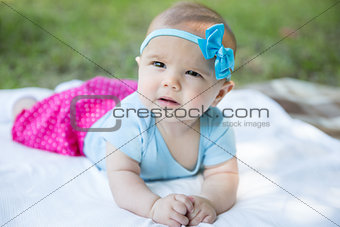 Baby girl crawling on the grass wearing blue bow