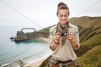 woman hiker viewing photos in front of ocean view landscape
