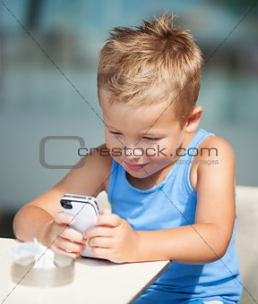 Portrait of blond kid using cell phone