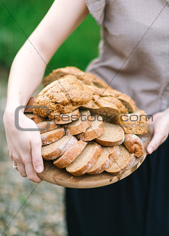 Woman holds in hand a wooden tray with the cut bread