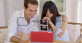 Blushing couple showing off ultrasound pictures