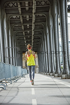 active woman running on Pont de Bir-Hakeim bridge in Paris