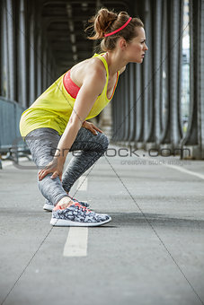 active woman stretching on Pont de Bir-Hakeim bridge in Paris