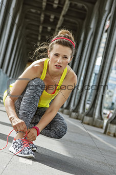 woman jogger tying shoelaces on Pont de Bir-Hakeim bridge, Paris