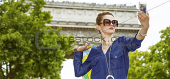trendy woman with shopping bags taking selfie in Paris, France