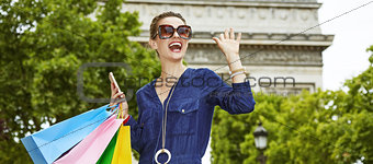 trendy woman with shopping bags handwaving in Paris, France