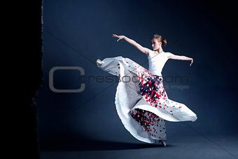 Young ballerina is dancing in a dark photostudio
