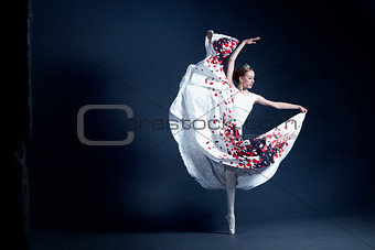 Young ballerina is dancing in a dark photostudio
