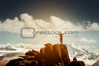 Man in winner pose with raised hands stands on the top of mountains. Win concept