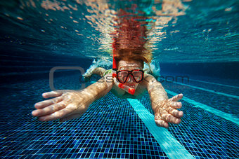 Man with snorkel mask and tube swims in swimming pool