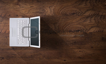 White laptop on a dark wooden desktop