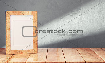 Blank frame on wooden table over gray background