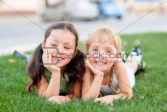Two little girls in roller skates laying on the grass